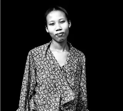 Black-and-white portrait of Alexandra Tomiyama against a dark background, wearing a floral-print shirt.