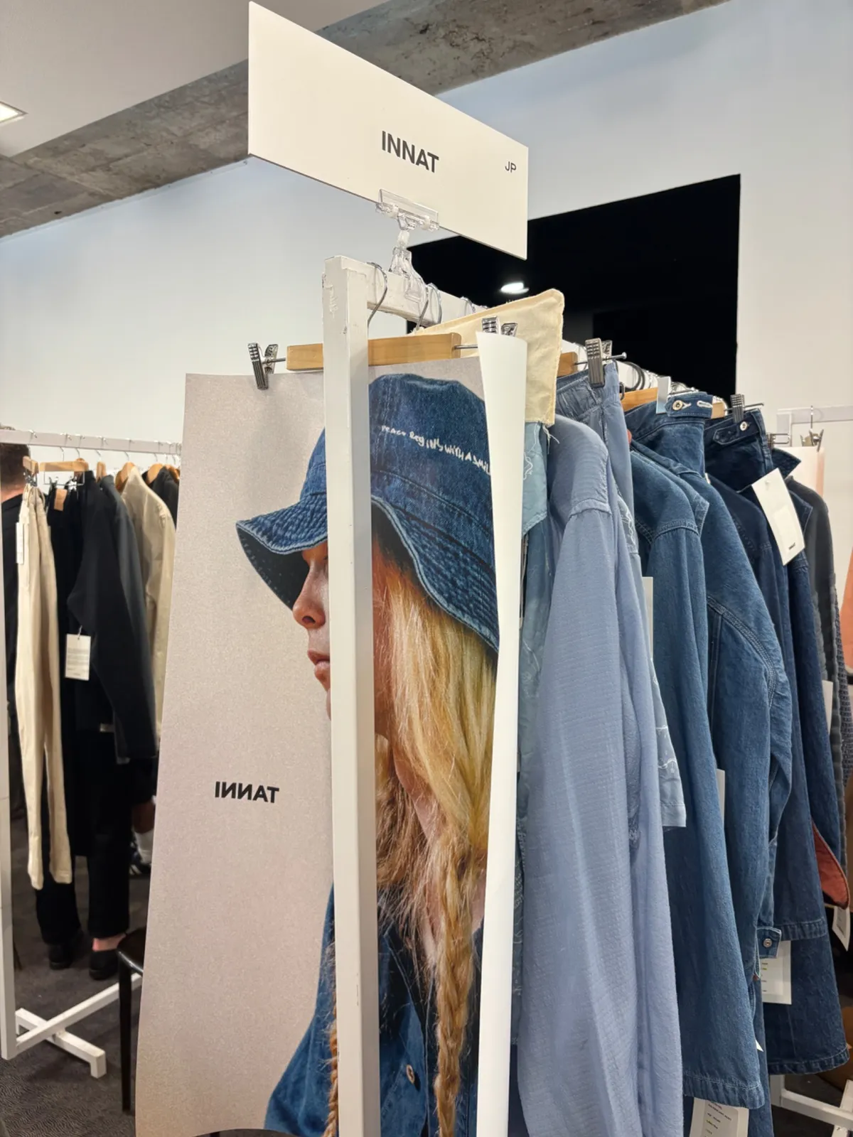 The brand's stand at MAN/WOMAN Paris: brand signage above a rail of denim pieces and a printed campaign board.